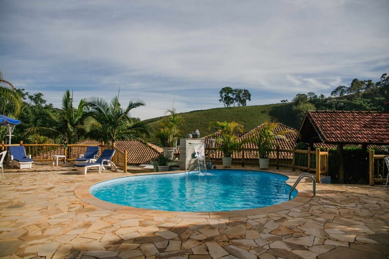 Piscina ao ar livre com espreguiçadeiras e vista para os morros de Cunha