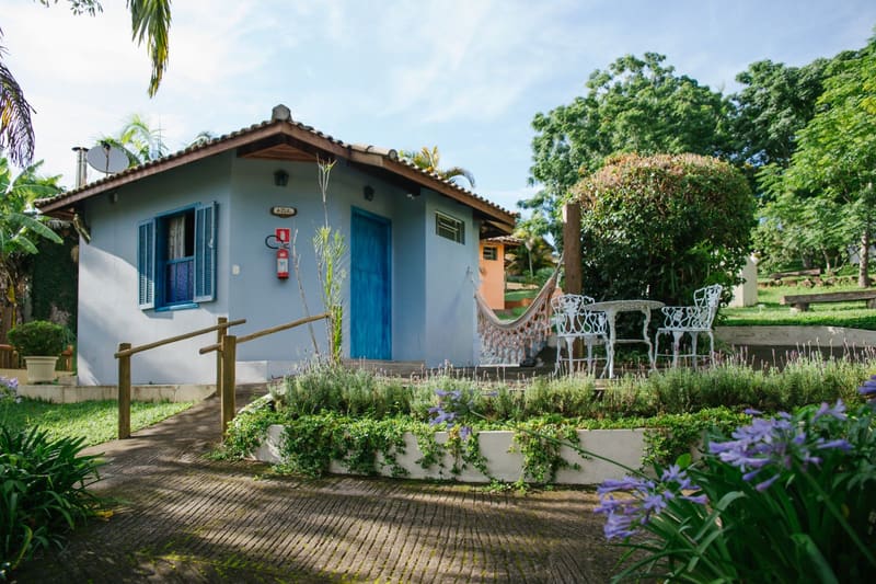 Chalés Jardim: chalé branco de janelas azuis com rede e jardim florido